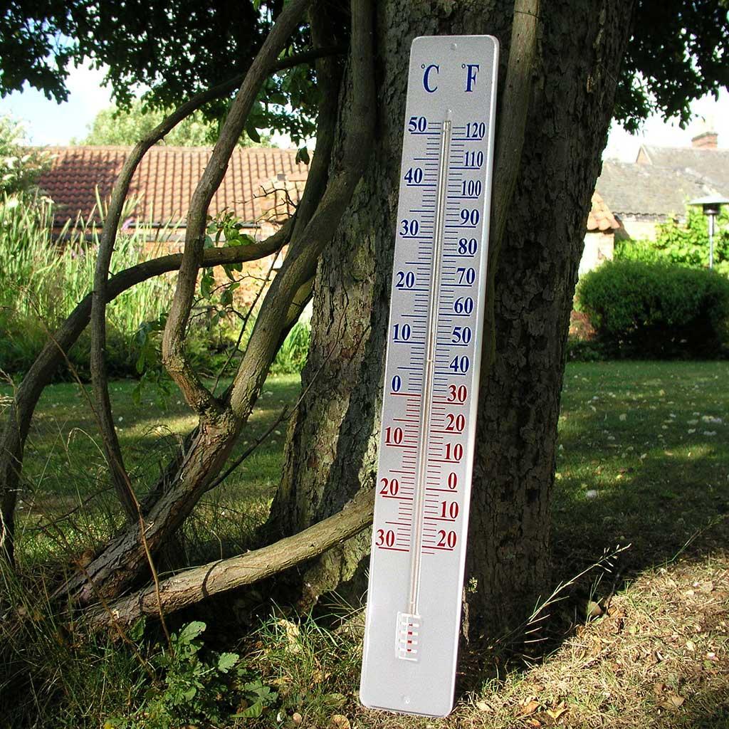 An outdoor thermometer hanging on the wall of a wooden garden shed