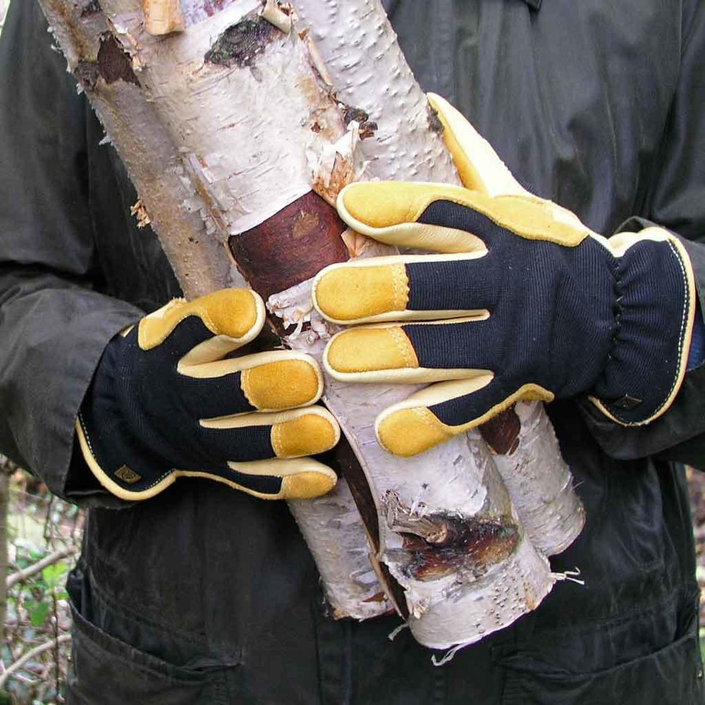 A gloved gardener carries firewood
