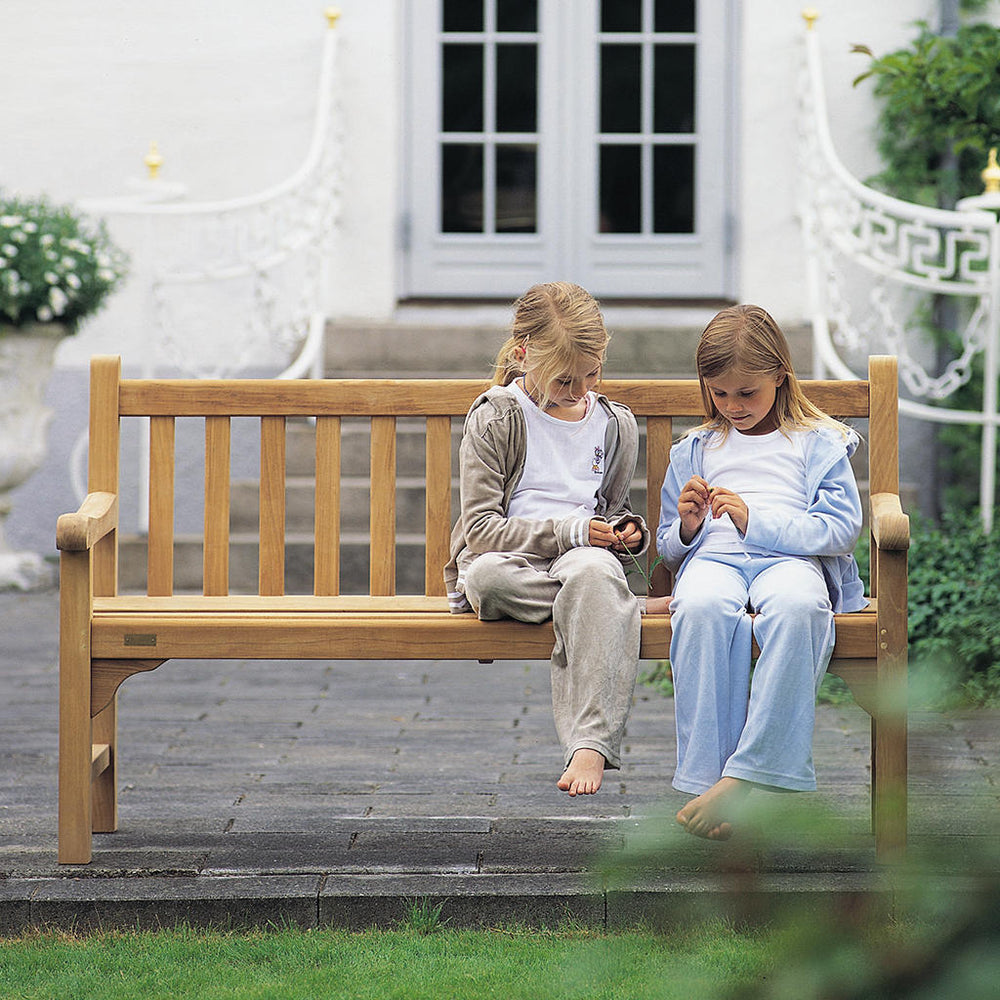 Two children sit playing on a traditional outdoor bench