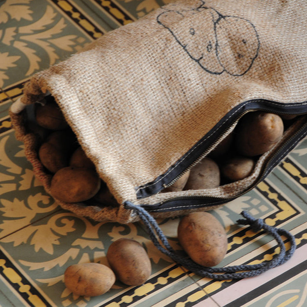 A jute sack of potatoes lays on the ground