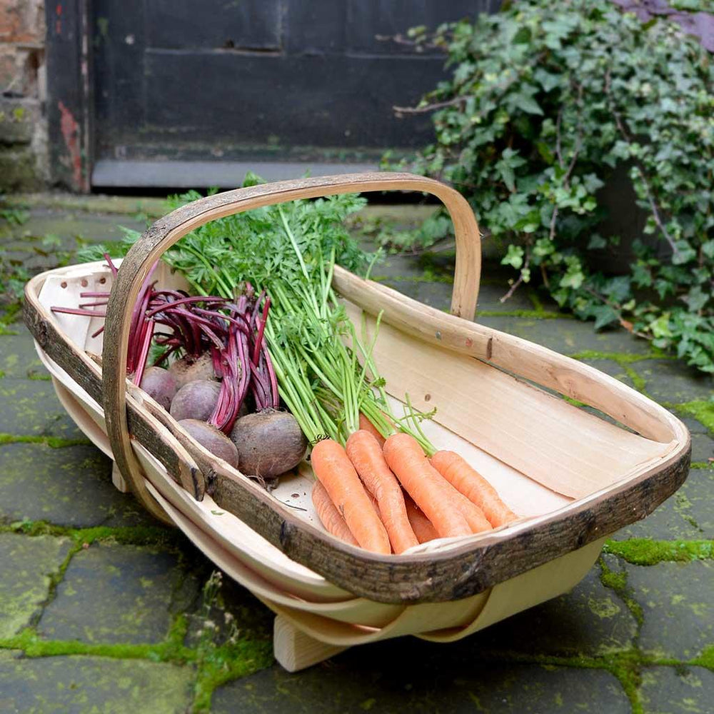 A wooden trug full of produce like carrots and beetrot